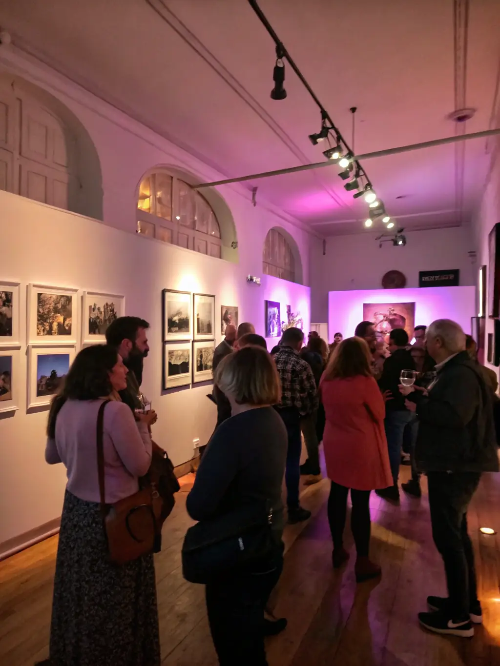 A photograph capturing the opening night of an art exhibition at PICT'ART EXPOS, featuring a diverse crowd admiring paintings and sculptures under warm lighting. The image should convey a sense of excitement and cultural engagement.
